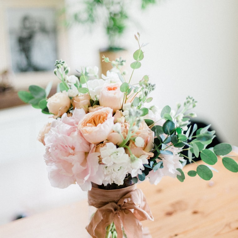 Bouquet de pivoines et de roses pastel noué d’un ruban de soie terracotta