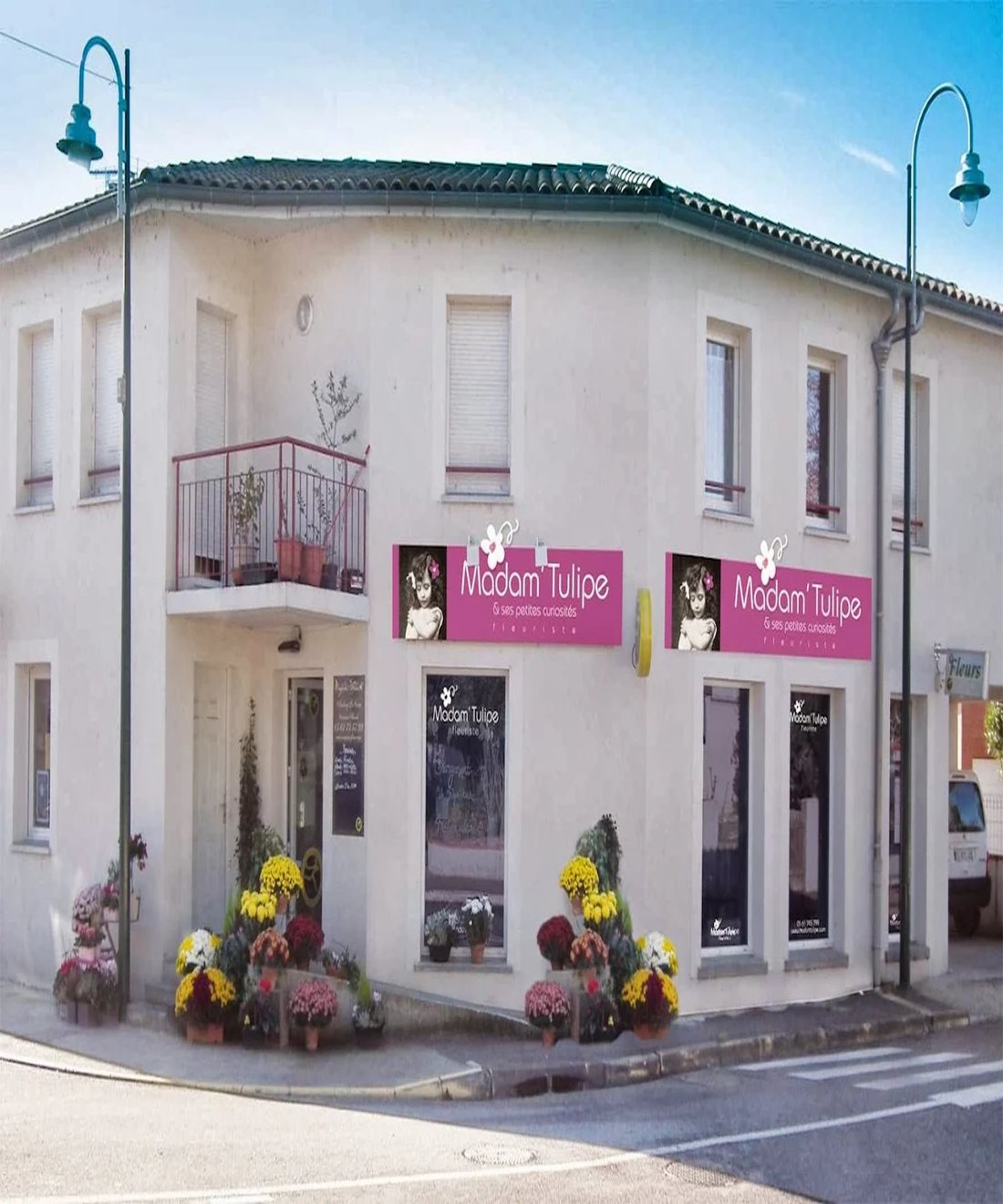 Devanture fleurie de la boutique, avec paniers suspendus, caisses en bois et bouquets de saison