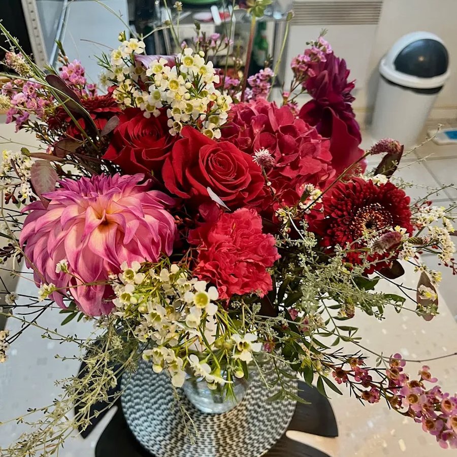 Composition riche en dahlias, roses rouges et fleurs sauvages